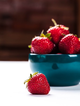 Red strawberries on blue clay plateの写真素材