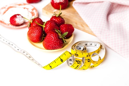 Strawberries with measuring tape on a white backgroundの写真素材