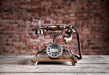 Old telephone on wooden background. Copy space on the bottom.の写真素材