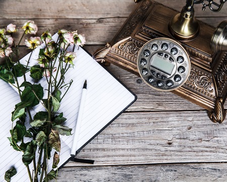 Old vintage black rotary phone and a bouquet of roses on wooden backgroundの写真素材