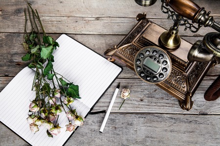 Old vintage black rotary phone and a bouquet of roses on wooden backgroundの写真素材