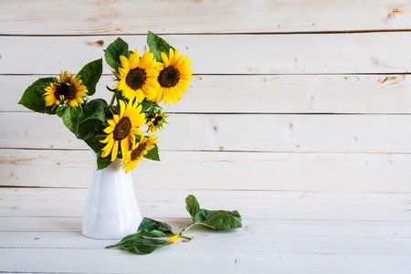 A bouquet of autumn sunflowers in a vase on a grungy wooden table.の写真素材