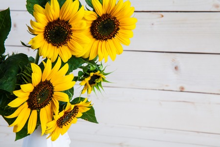 A bouquet of autumn sunflowers in a vase on a grungy wooden table.の写真素材