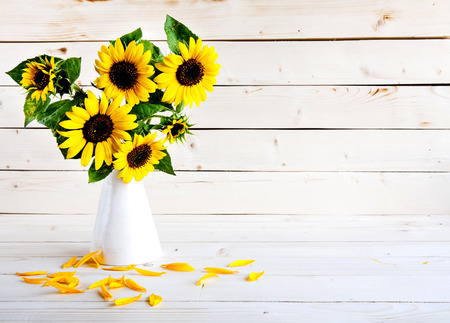 A bouquet of autumn sunflowers in a vase on a grungy wooden table.の写真素材