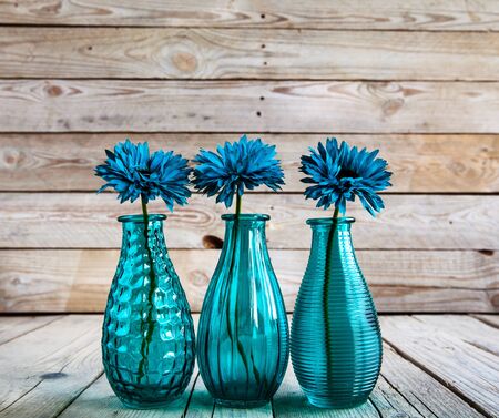 blue gerbera flower in a vase on wooden backgroundの写真素材