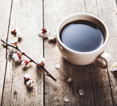 Cherry blossoms on a wooden background with a cup of coffeeの写真素材