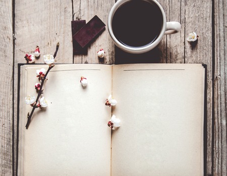 Open vintage book with blossom branch of cherry-tree on  wooden tableの写真素材