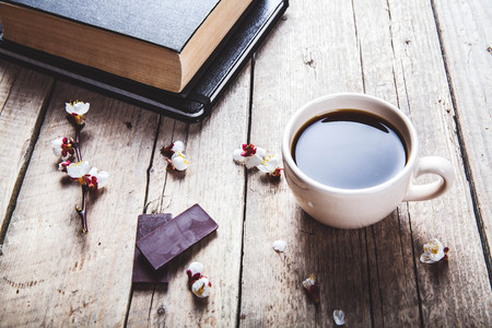 Open vintage book with blossom branch of cherry-tree on  wooden table. a cup of coffeeの写真素材