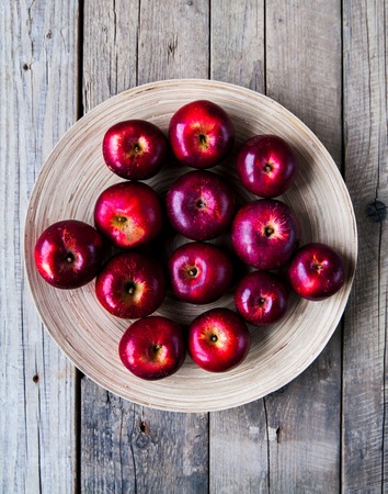 Fresh harvest of apples. Nature theme with red grapes and basket on wooden background. Nature fruit concept.の写真素材