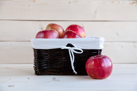 Basket with red apples on wooden backgroundの写真素材