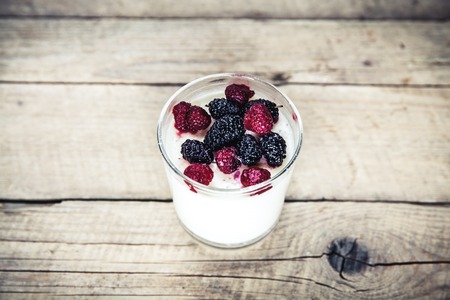 Healthy breakfast - Dairy yogurt with raspberry, mulberry on wooden backgroundの写真素材