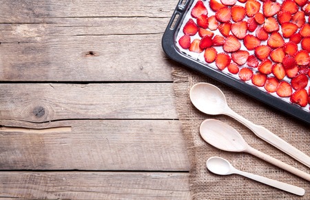 fruit. sliced Strawberry with wooden spoons baking on a dark metal plate in oven. wood backgroundの写真素材