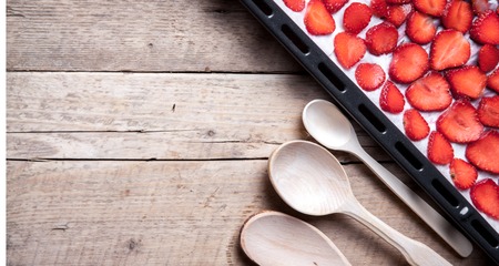 fruit. sliced Strawberry with wooden spoons baking on a dark metal plate in oven. wood backgroundの写真素材
