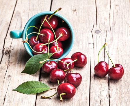 Cherries in the beautiful turquoise cup on wooden table, macro background, fruits, berriesの写真素材