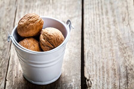 pecan nuts in a bucket on a wooden background