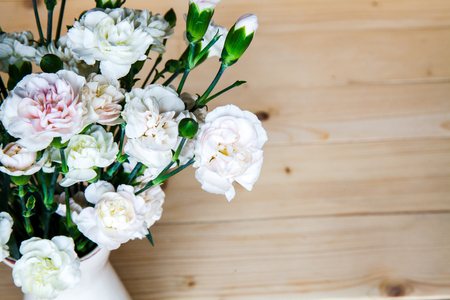 delicate bouquet of carnations in a vase on a vintage wooden backgroundの写真素材