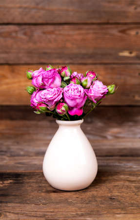 pink roses in a vase on wooden background. flowersの写真素材