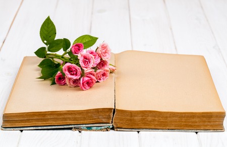 Roses on an old book on white wooden background. flowersの写真素材
