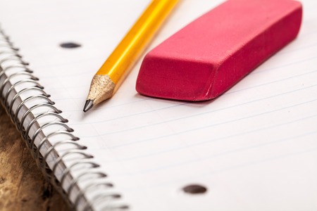 Open notebook with blank page and pencil and eraser. Wooden floor in the background.の写真素材
