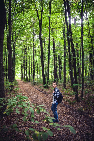 Portrait of young handsome man with backpack wanderer walk in the woods while enjoying the nature...