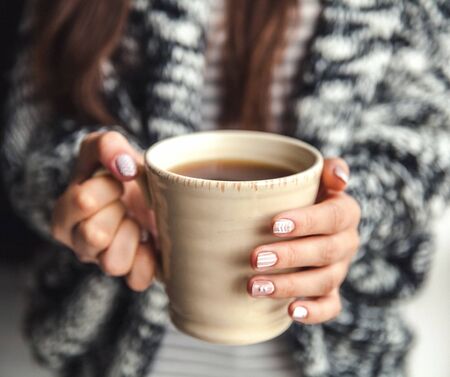Girl's hands holding a cup of coffeeの写真素材