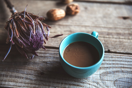 A Cup of coffee on wooden background, with flower and nuts.の写真素材