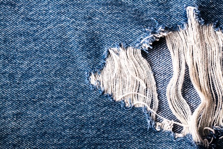 blue jean texture with a hole and threads showingの写真素材