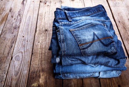 jeans stacked on a wooden backgroundの写真素材