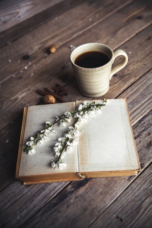 Large Cup of coffee on vintage wooden background. Spring flowers and books.の写真素材