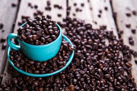 Turquoise cup with coffee beans on a wooden background.の写真素材