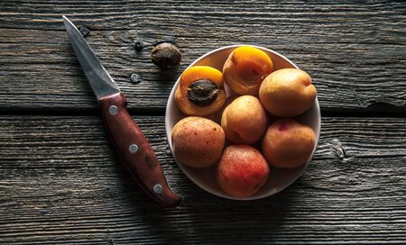 Apricots with a knife on a wooden background.