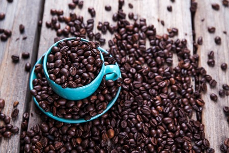 Turquoise cup with coffee beans on a wooden background. Beverage, tablewareの写真素材