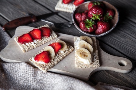 Fruity toast on wooden background. Strawberries, bread, butter and cheese.Vintage styleの写真素材