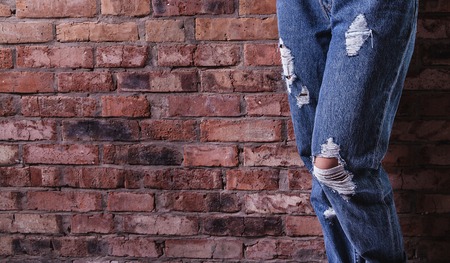 retro ripped jeans and a beautiful manicure on a background of a brick wall. Fashion styleの写真素材