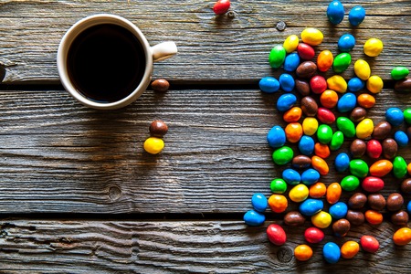 colored sweets with coffee on a wooden background