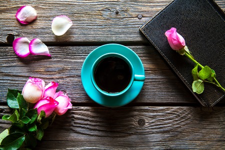 Fresh roses with diary and cup of coffee on wooden table, top view. flowers, hot drinkの写真素材