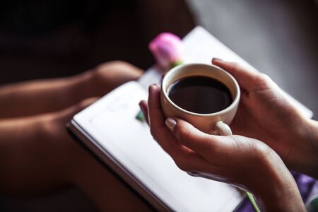 Girl reading book and drinking coffee, beautiful rose. Morning, hobbies, flowers, studyの写真素材