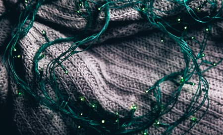 Christmas and garlands. Winter cozy concept. Flatlay of gray knitted sweater. Warm weekend in cold...