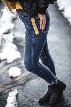 Knee figure of young beautiful blonde straight hair woman in the city, one hand in pocket - eyes closed - serenity, carefreeness concept - wearing jeans overalls and jacket aの写真素材