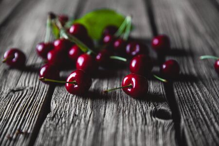 Wooden  with several delicious cherries on green leaves