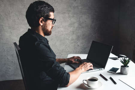 A man sits with a laptop in a black shirt. Business concept, work. Office routine. Property effortsの写真素材
