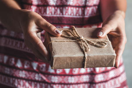 Female wearing a red with red christmas dress has a christmas gift in her hands. manicureの写真素材