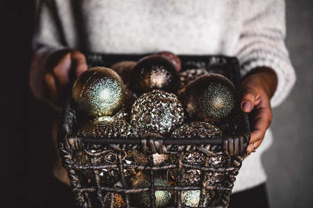 Wire basket full of Christmas or New Year tree golden vintage decoration toys in hands of lady, selective focus, square cropの写真素材