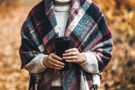 Woman hold cup in forest, autumn photographの写真素材