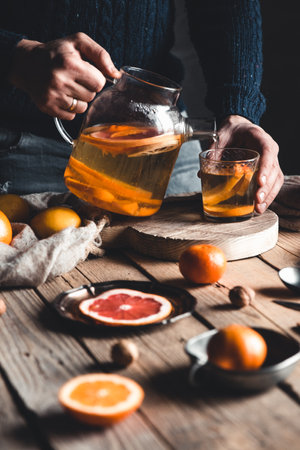A man pours citrus tea on a wooden table. Healthy drink, vintage style. Vegan, eco products.の写真素材