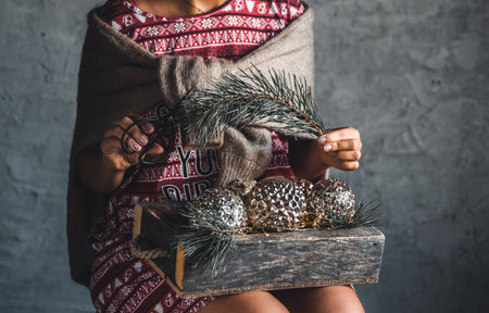 Girl in a Christmas dress holds balls in a wooden box, holiday, comfortの写真素材