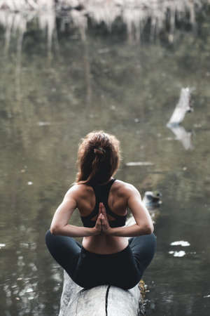 Girl go in for sports in the forest. In the lotus position. Exercises, gymnastics, relaxation. Healthy lifestyle.の写真素材