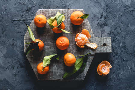Group of three whole one piece of fresh orange mandarin on wooden cutting board.の写真素材