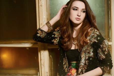beautiful young brunette woman in a black jacket with sequins and bright skirtの写真素材