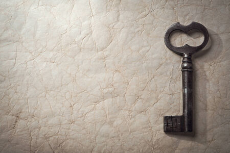 Ancient key on a crumpled paper, top view. Background.の写真素材